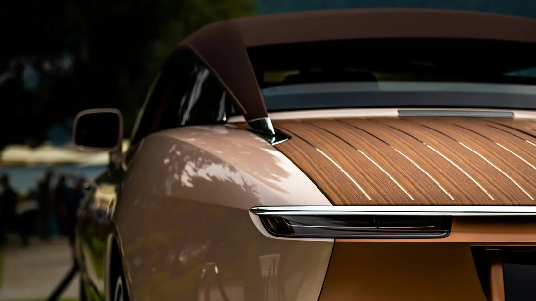 Nahaufnahme des Hecks eines champagnerfarbenen Luxusautos mit einem edlen Holzdeck im Yacht-Stil, das extremen finanziellen Erfolg symbolisiert.